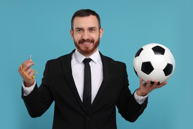 Photo of Happy young man with soccer ball and whistle on light blue background