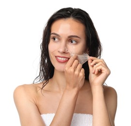 Smiling woman peeling off face mask on white background