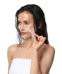 Beautiful woman peeling off face mask on white background