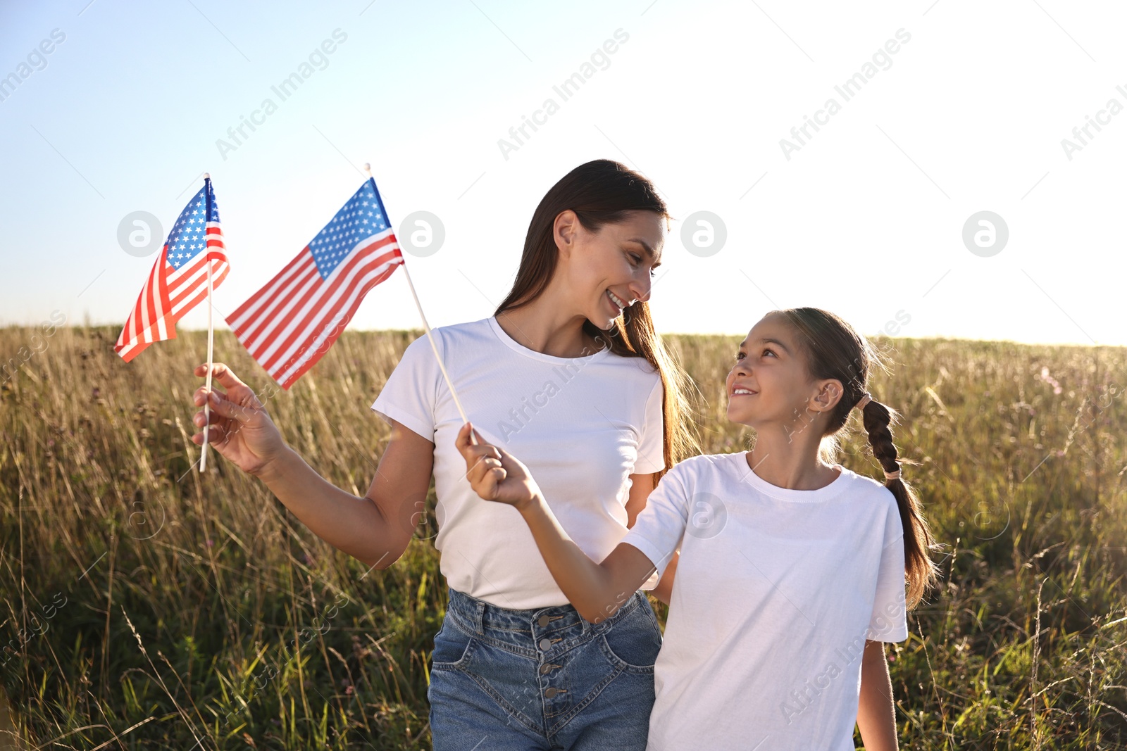 Photo of Happy mother and daughter with flags of USA outdoors