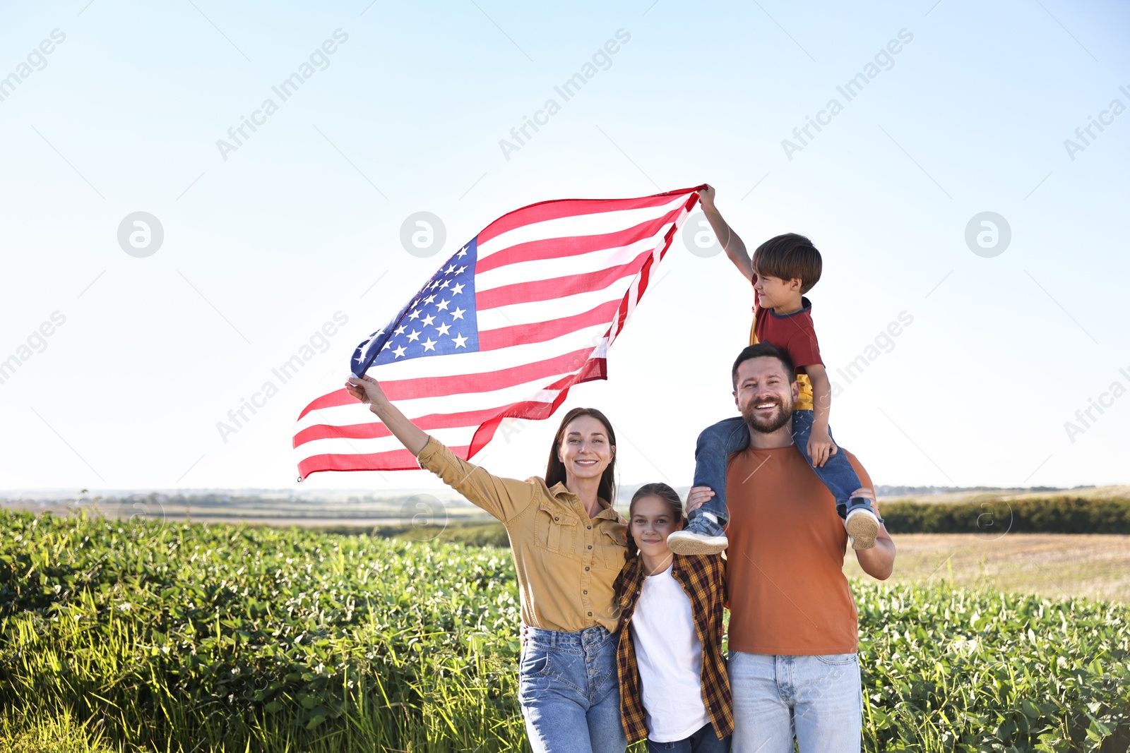 Photo of Happy family with flag of USA outdoors. Space for text