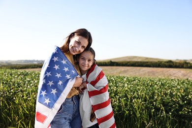 Happy mother and daughter with flag of USA outdoors. Space for text