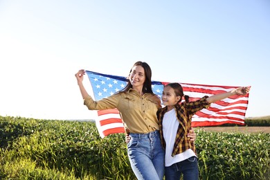 Happy mother and daughter with flag of USA outdoors. Space for text