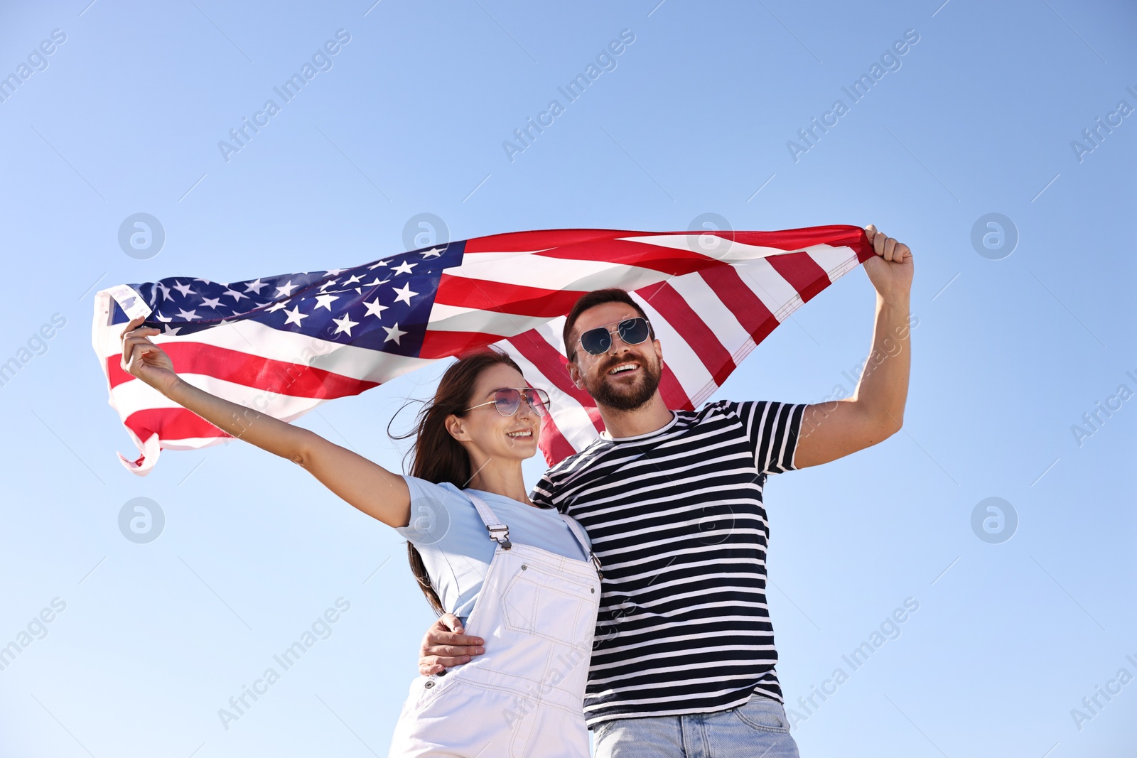 Photo of Happy couple with flag of USA outdoors, low angle view