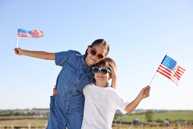 Photo of Brother and sister with flags of USA outdoors