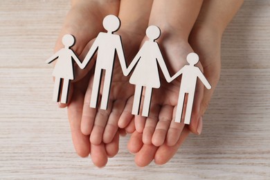 Photo of Adoption concept. Woman and kid with cutout of family at white wooden table, top view