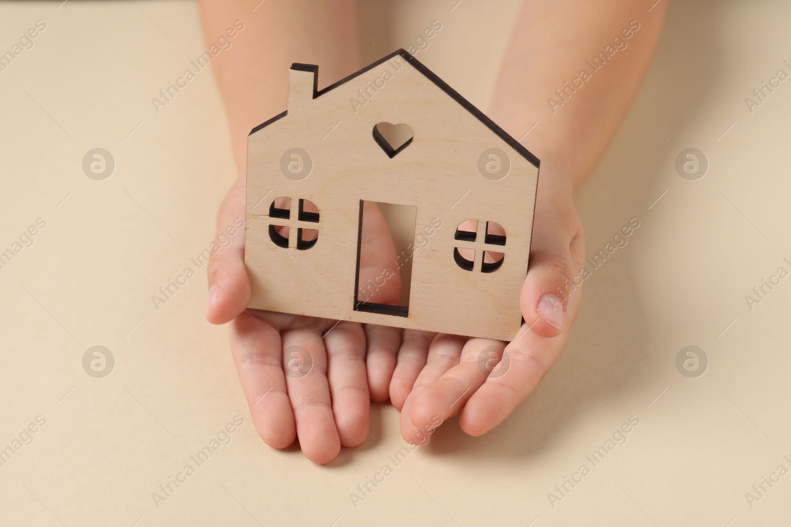 Photo of Adoption concept. Kid with cutout of house at beige table, closeup