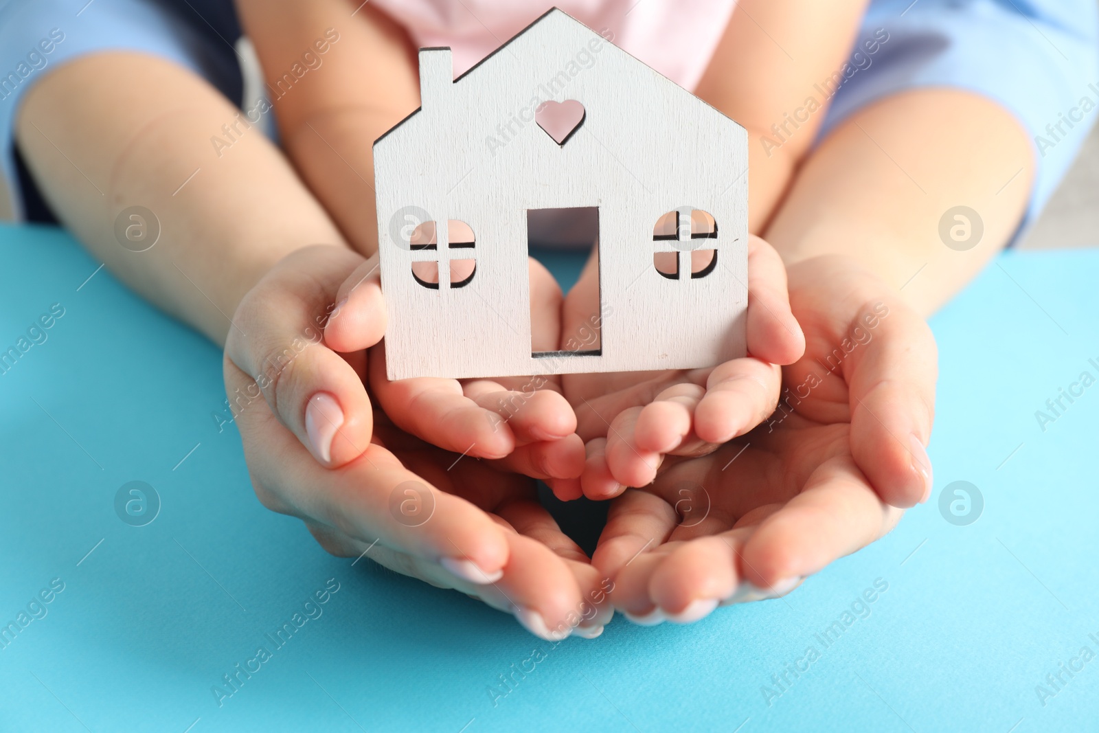 Photo of Adoption concept. Woman and kid with cutout of house at light blue background, closeup