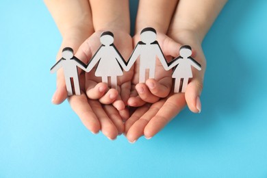 Photo of Adoption concept. Woman and kid with cutout of family at light blue background, closeup