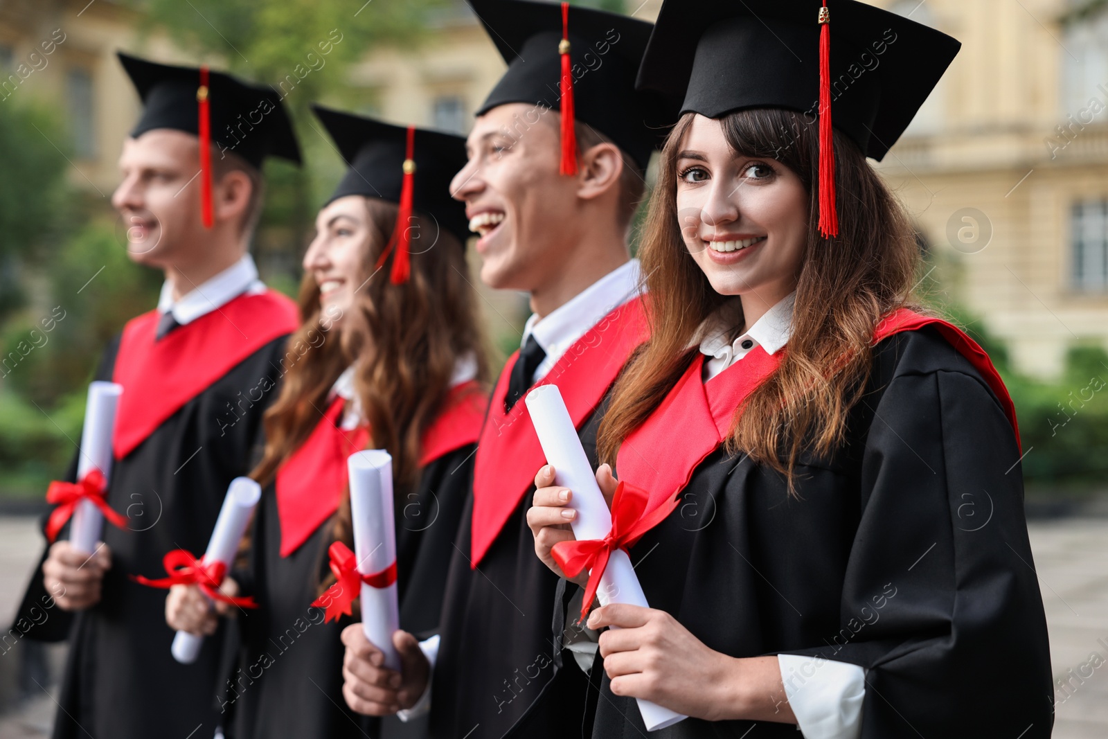 Photo of Happy students with diplomas after graduation ceremony outdoors, selective focus