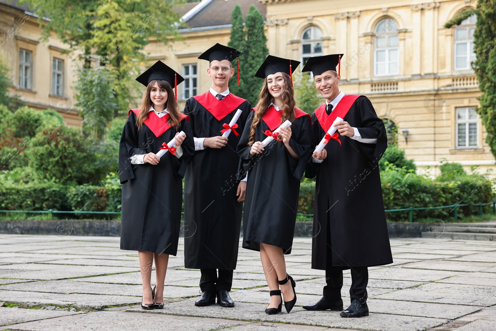 Photo of Happy students with diplomas after graduation ceremony outdoors