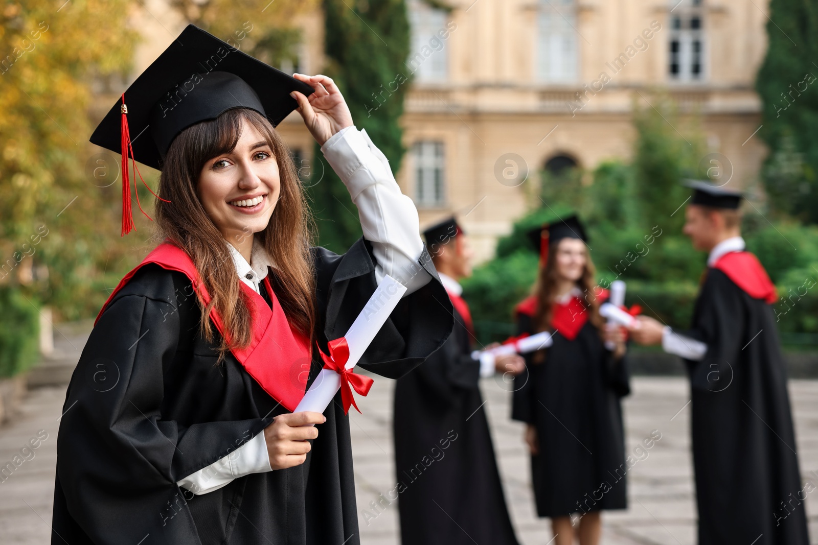 Photo of Happy students with diplomas after graduation ceremony outdoors, selective focus