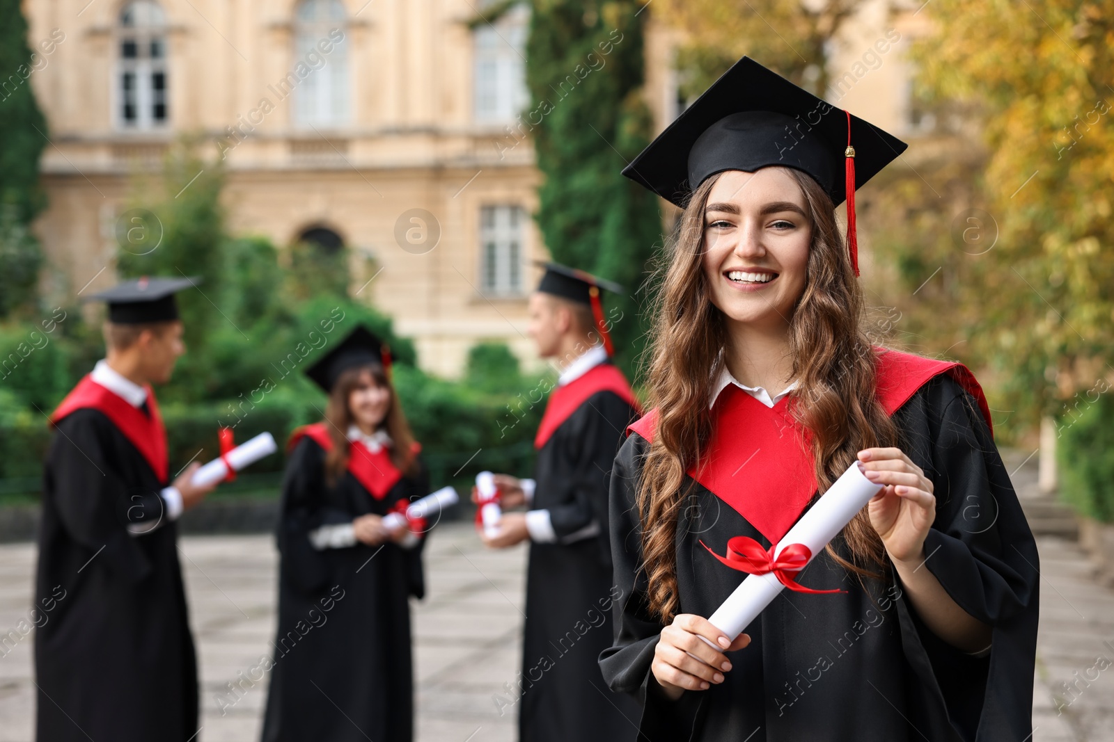 Photo of Happy students with diplomas after graduation ceremony outdoors, selective focus