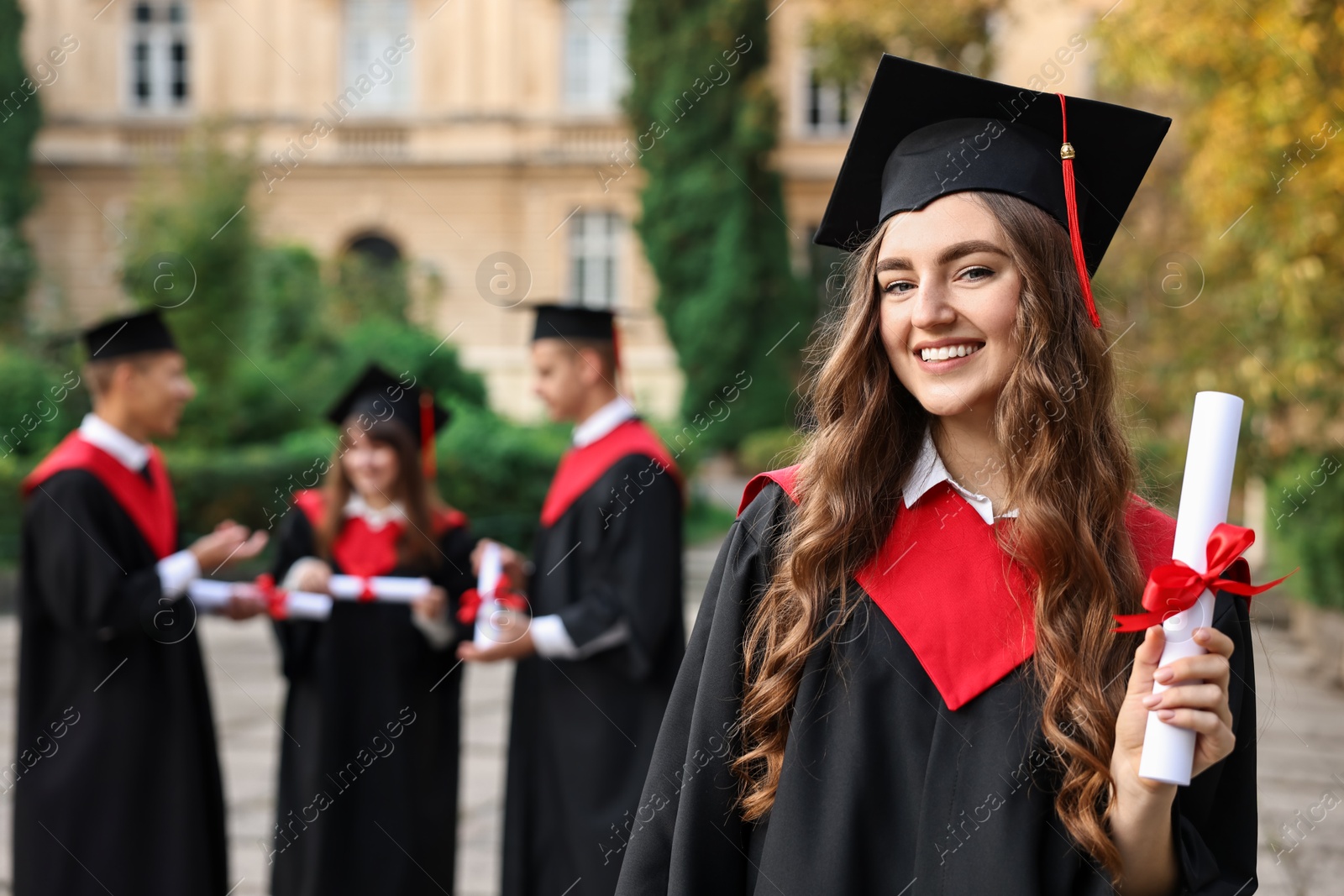 Photo of Happy students with diplomas after graduation ceremony outdoors, selective focus