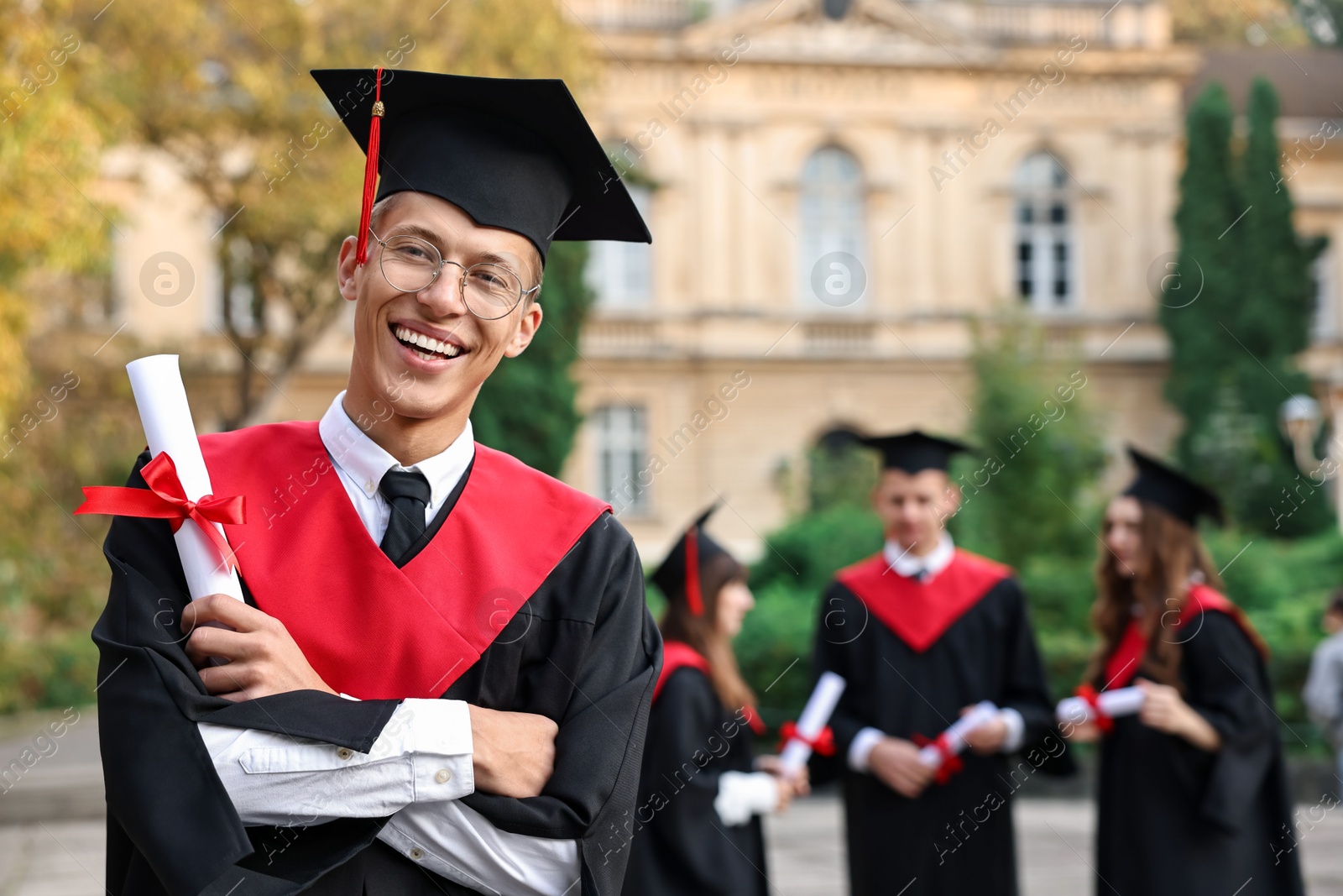 Photo of Happy students with diplomas after graduation ceremony outdoors, selective focus