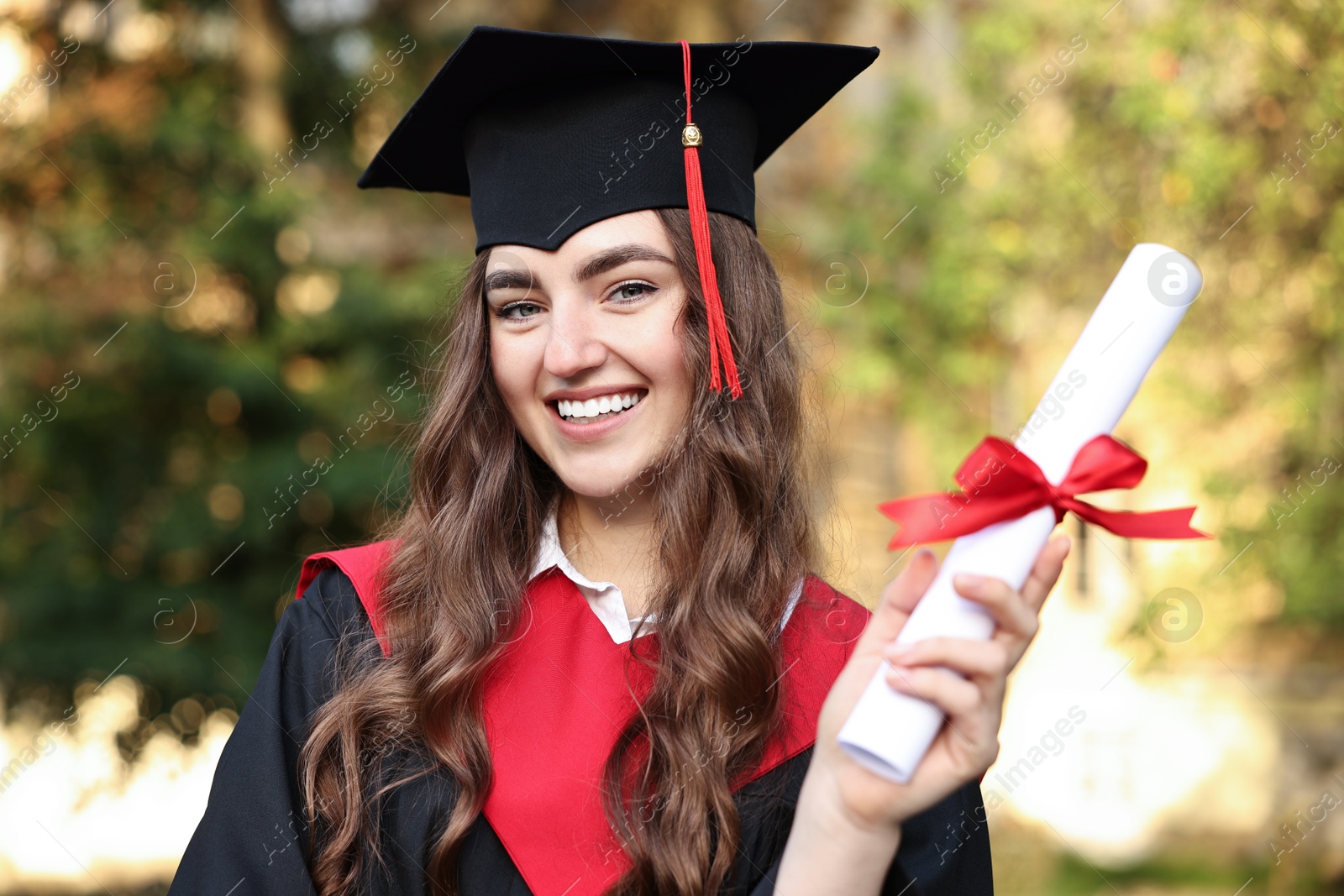 Photo of Happy student with diploma after graduation ceremony outdoors