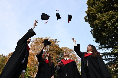 Photo of Graduation ceremony. Group of students throwing hats outdoors, low angle view