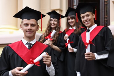 Photo of Graduation ceremony. Happy students with diplomas outdoors, selective focus