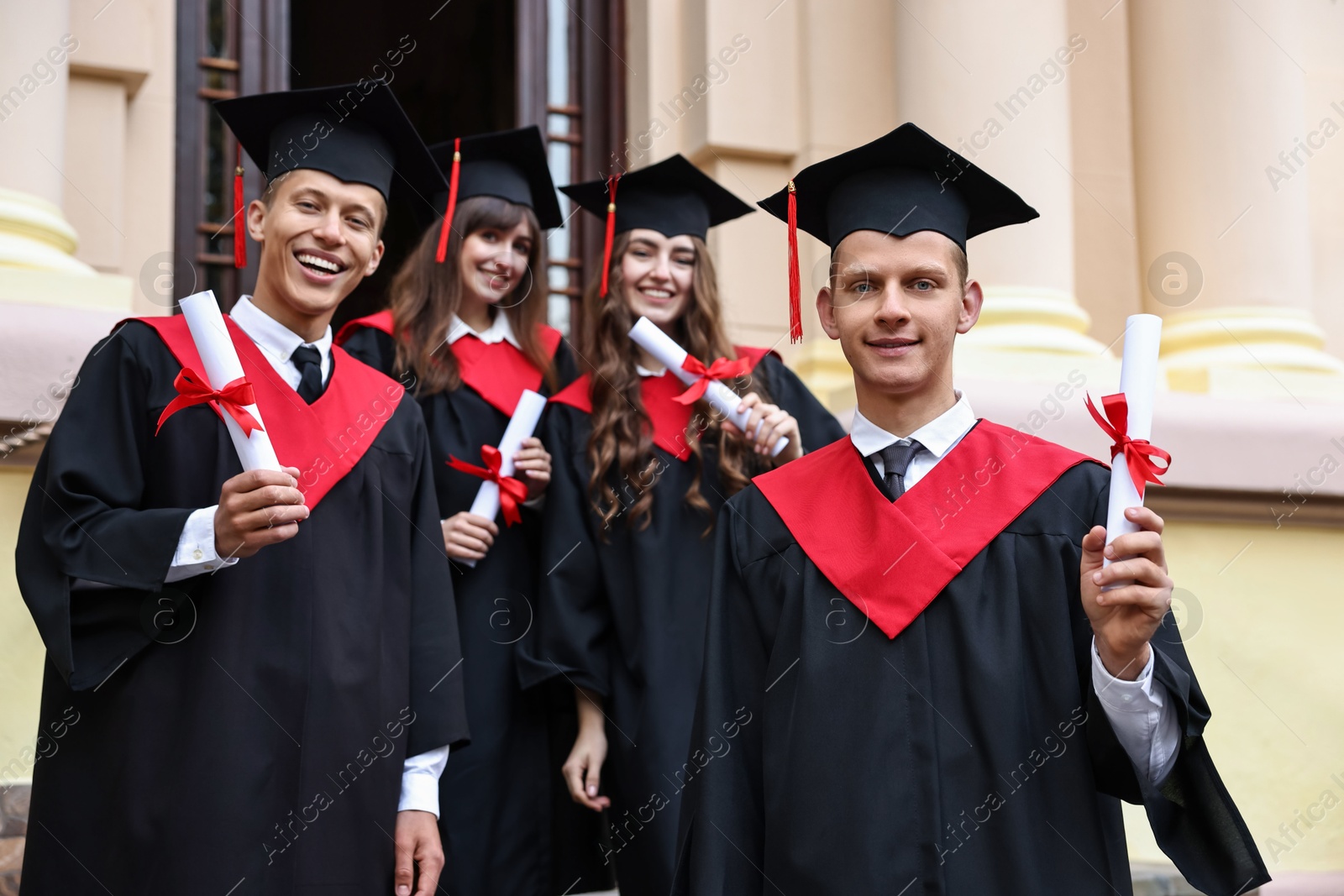 Photo of Graduation ceremony. Happy students with diplomas outdoors, selective focus