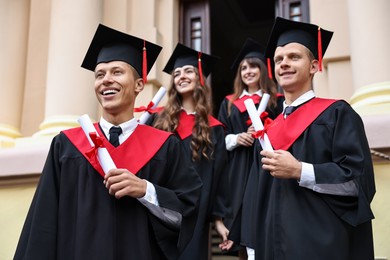 Graduation ceremony. Happy students with diplomas outdoors, selective focus