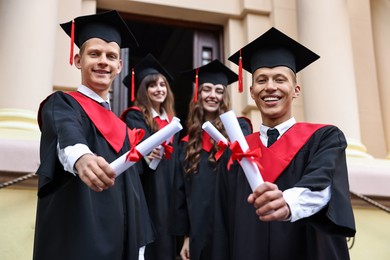 Photo of Graduation ceremony. Happy students with diplomas outdoors, selective focus