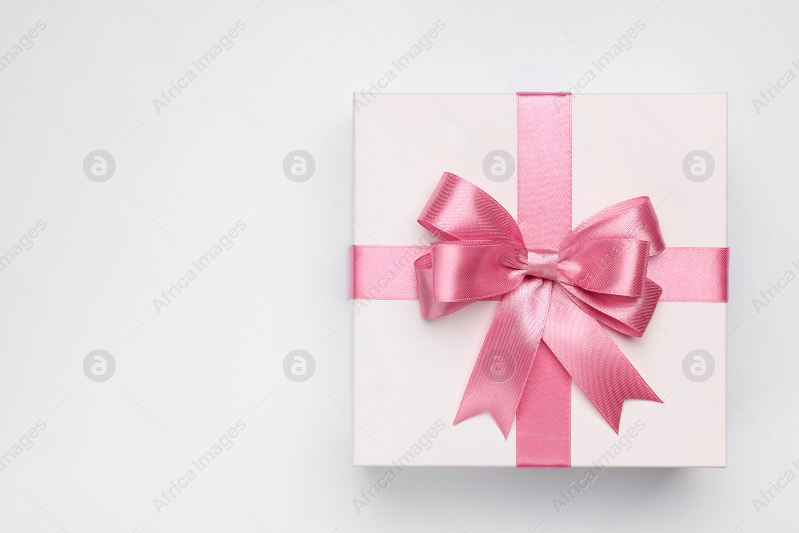 Photo of Gift box with pink bow on light grey background, top view. Space for text