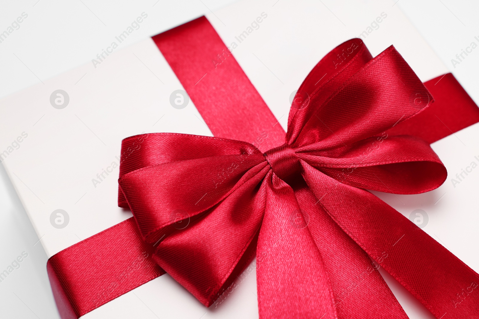 Photo of Gift box with red bow on light grey background, closeup