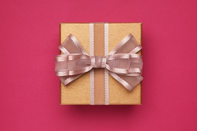 Photo of Gift box with bow on burgundy background, top view