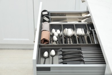 Photo of Box with cutlery in drawer indoors. Kitchen utensils storage