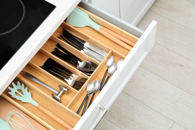 Photo of Box with cutlery in drawer, closeup. Kitchen utensils storage