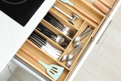 Photo of Box with cutlery in drawer, closeup. Kitchen utensils storage