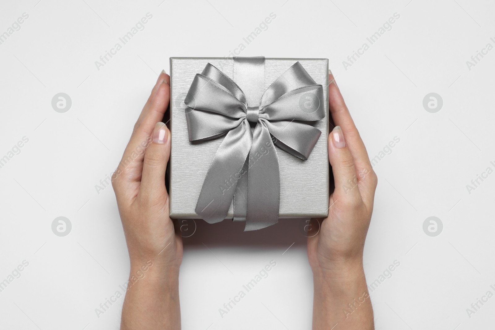 Photo of Woman holding gift box with bow on white background, top view