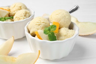 Photo of Scoops of melon sorbet with mint and fresh fruit in bowls on white wooden table, closeup