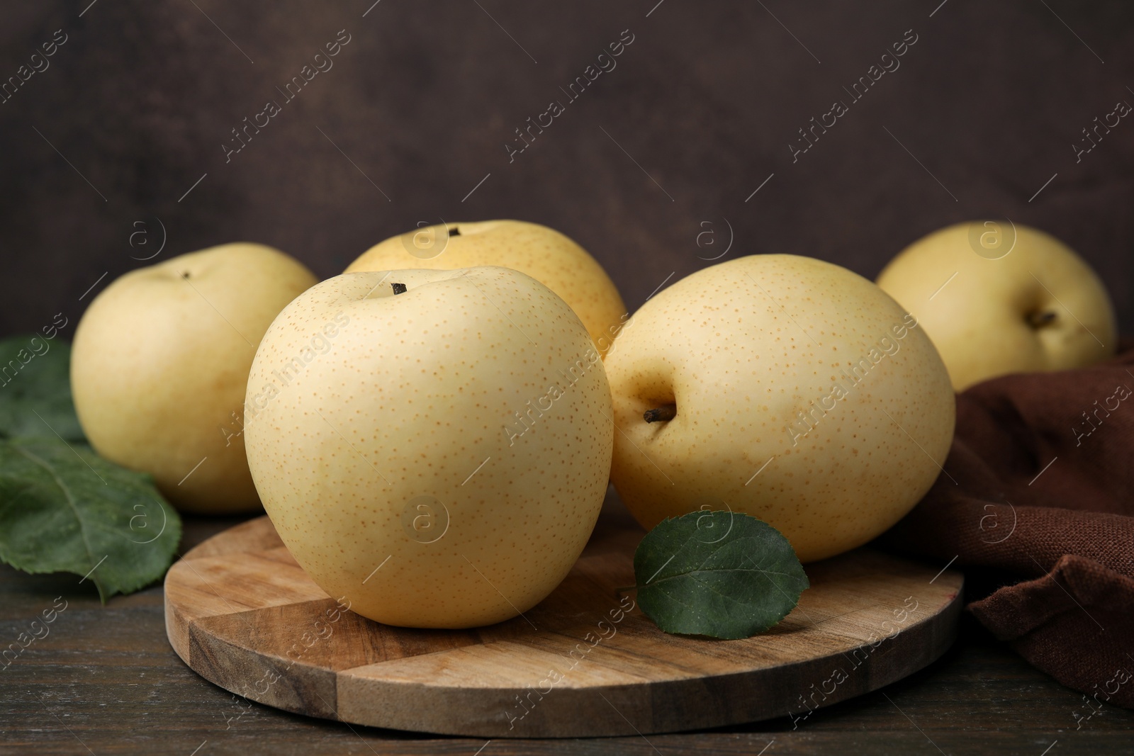 Photo of Delicious fresh apple pears and green leaves on wooden table, closeup