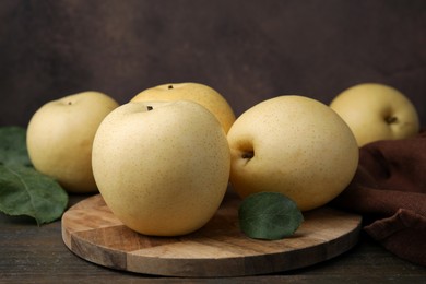 Photo of Delicious fresh apple pears and green leaves on wooden table, closeup