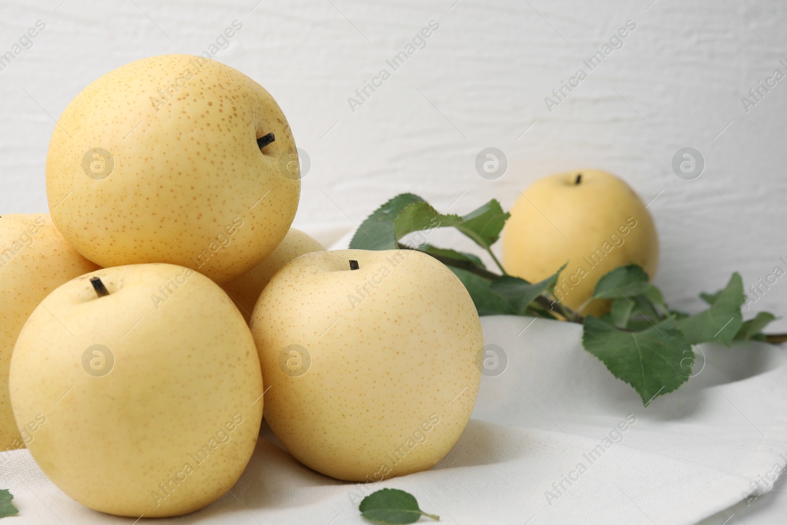 Photo of Delicious fresh apple pears and green leaves on table, closeup