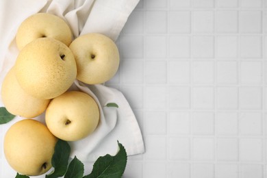 Photo of Delicious fresh apple pears and leaves on white tiled table, top view. Space for text