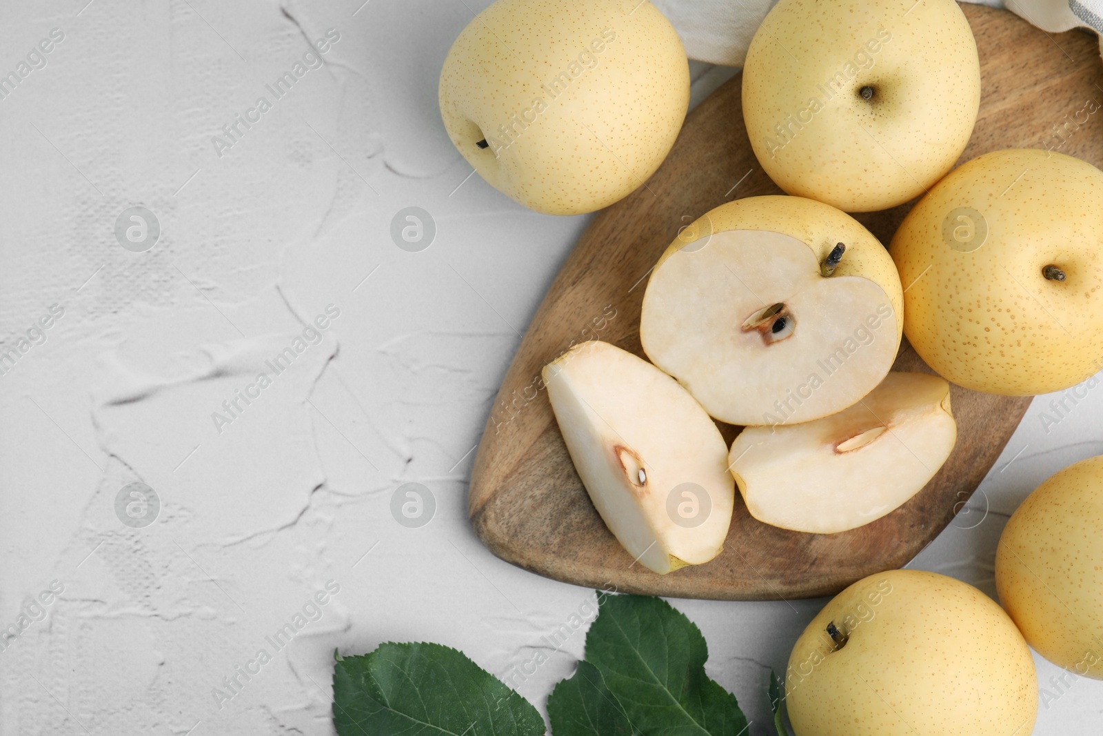 Photo of Delicious fresh apple pears and leaves on white table, top view. Space for text