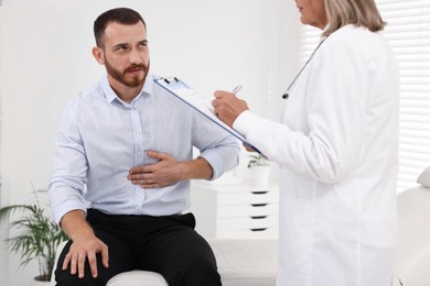 Photo of Doctor consulting patient with stomach pain in clinic, closeup