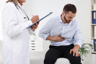 Doctor consulting patient with stomach pain in clinic, closeup