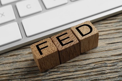 Photo of Cubes with letters Fed (Federal Reserve System) and keyboard on wooden table