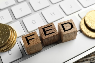 Photo of Wooden cubes with letters Fed (Federal Reserve System), keyboard and coins on table