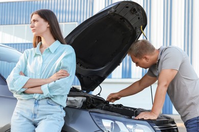 Man and woman near broken car outdoors