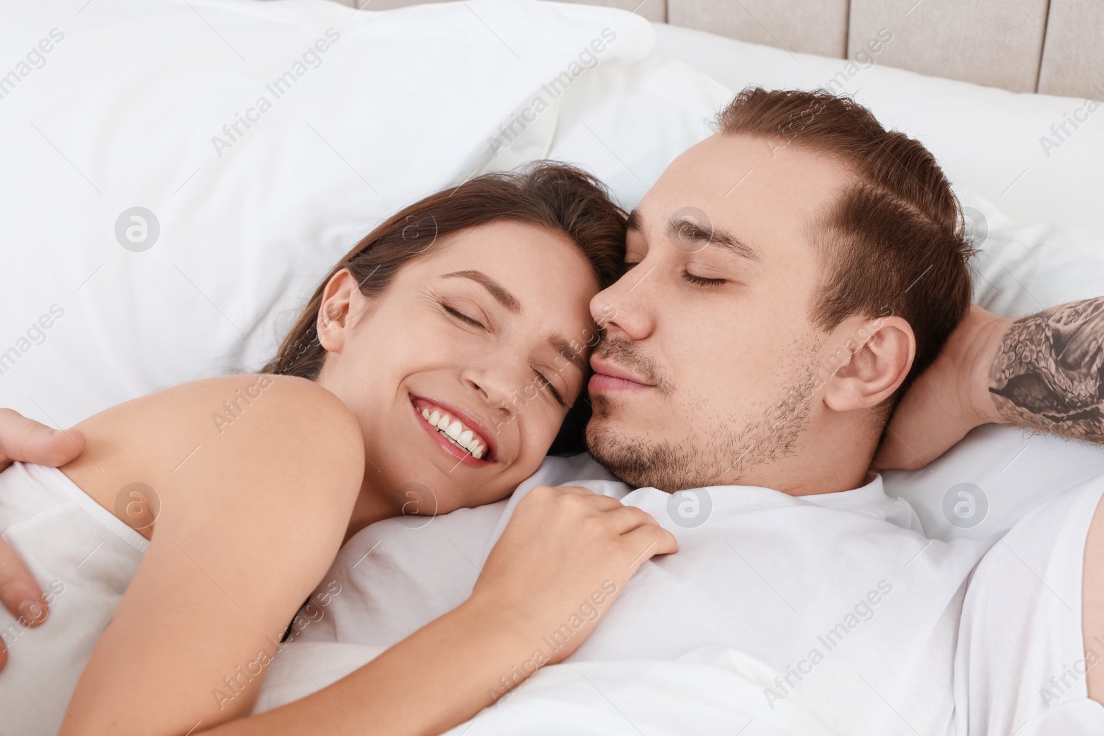 Photo of Happy couple lying on bed at home