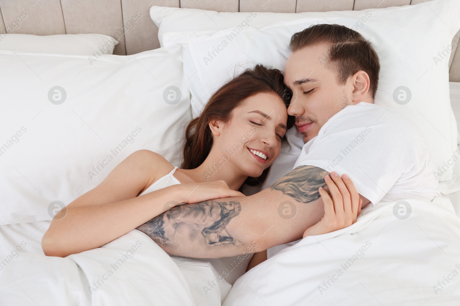 Photo of Happy couple lying on bed at home