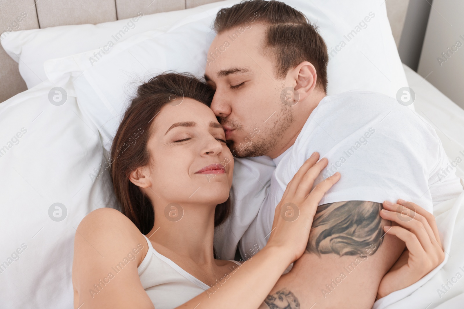 Photo of Happy couple lying on bed at home