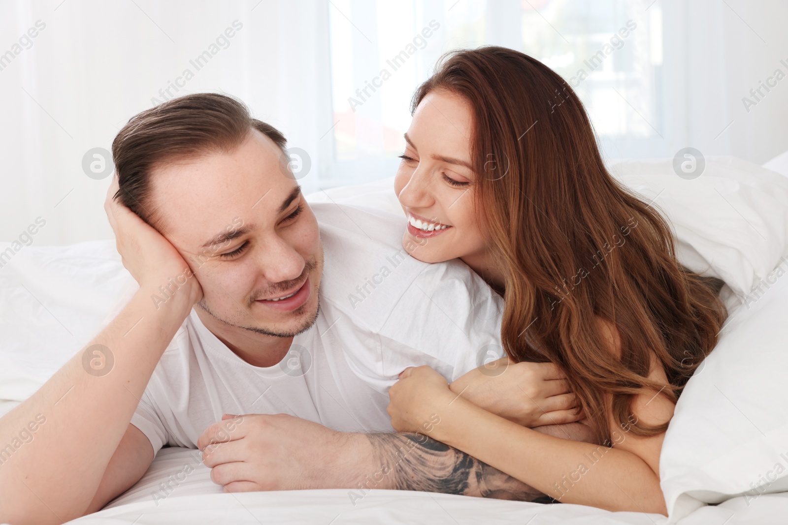 Photo of Happy couple spending time together on bed at home