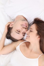 Photo of Happy couple spending time together on bed at home, top view