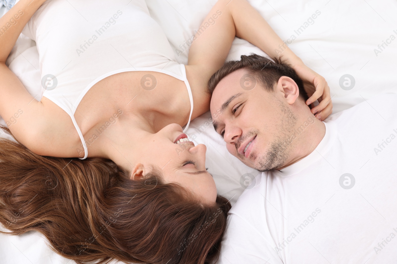 Photo of Happy couple spending time together on bed at home, top view