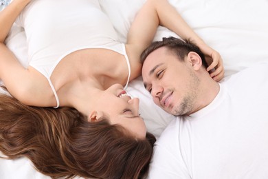 Happy couple spending time together on bed at home, top view